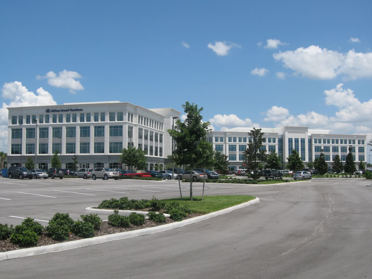 A large parking lot in front of two white buildings