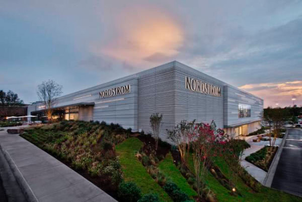 A hill covered in grass and shrubs in front of a department store