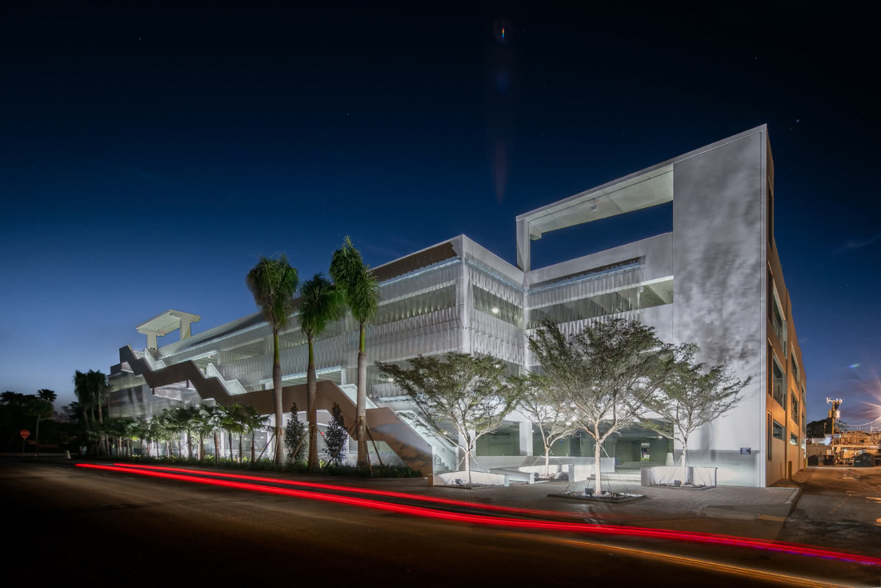 The side of a white parking garage at dusk